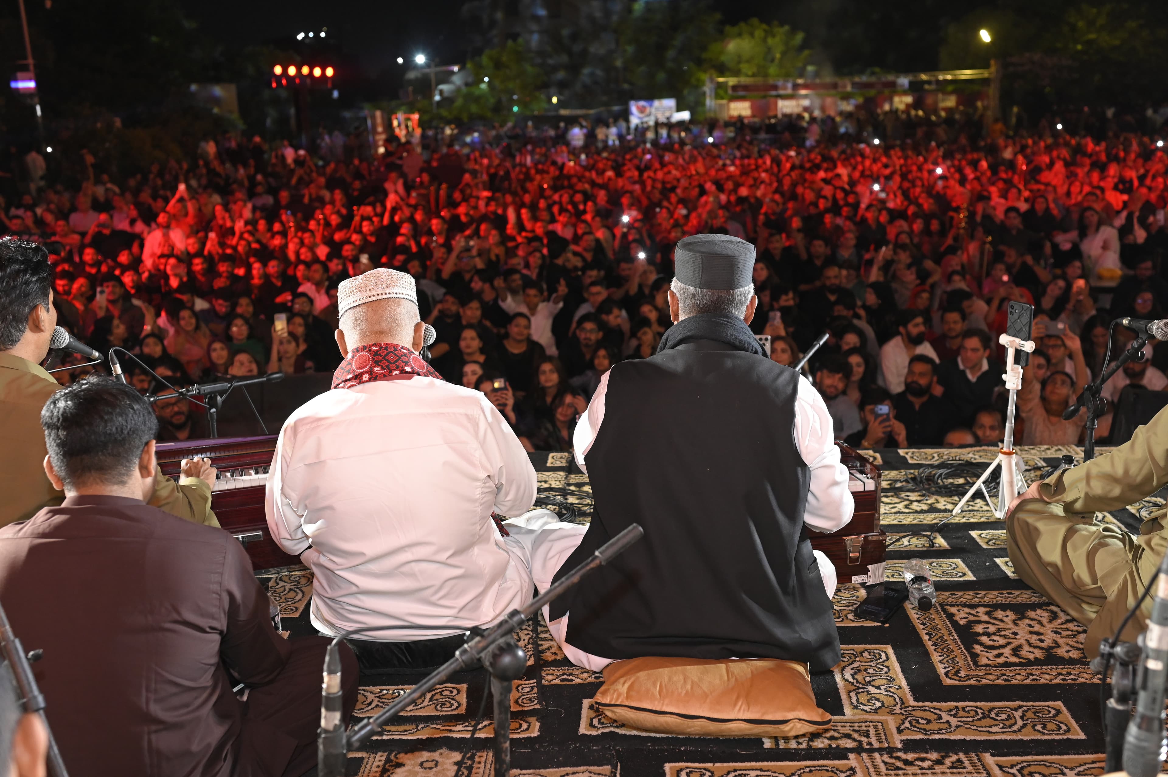 Two Qawwals seen from behind facing a massive red-lit crowd at SMASH FEST Season 2